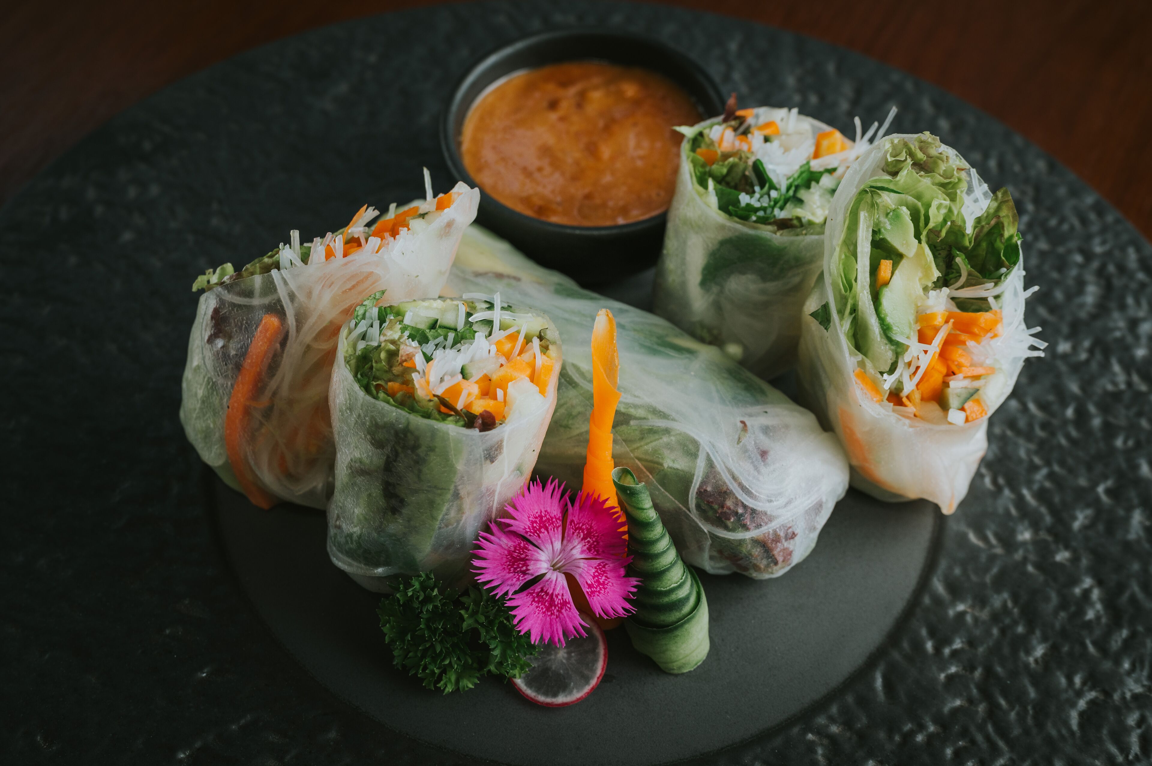 A plate of Vietnamese spring rolls with a side of dipping sauce.