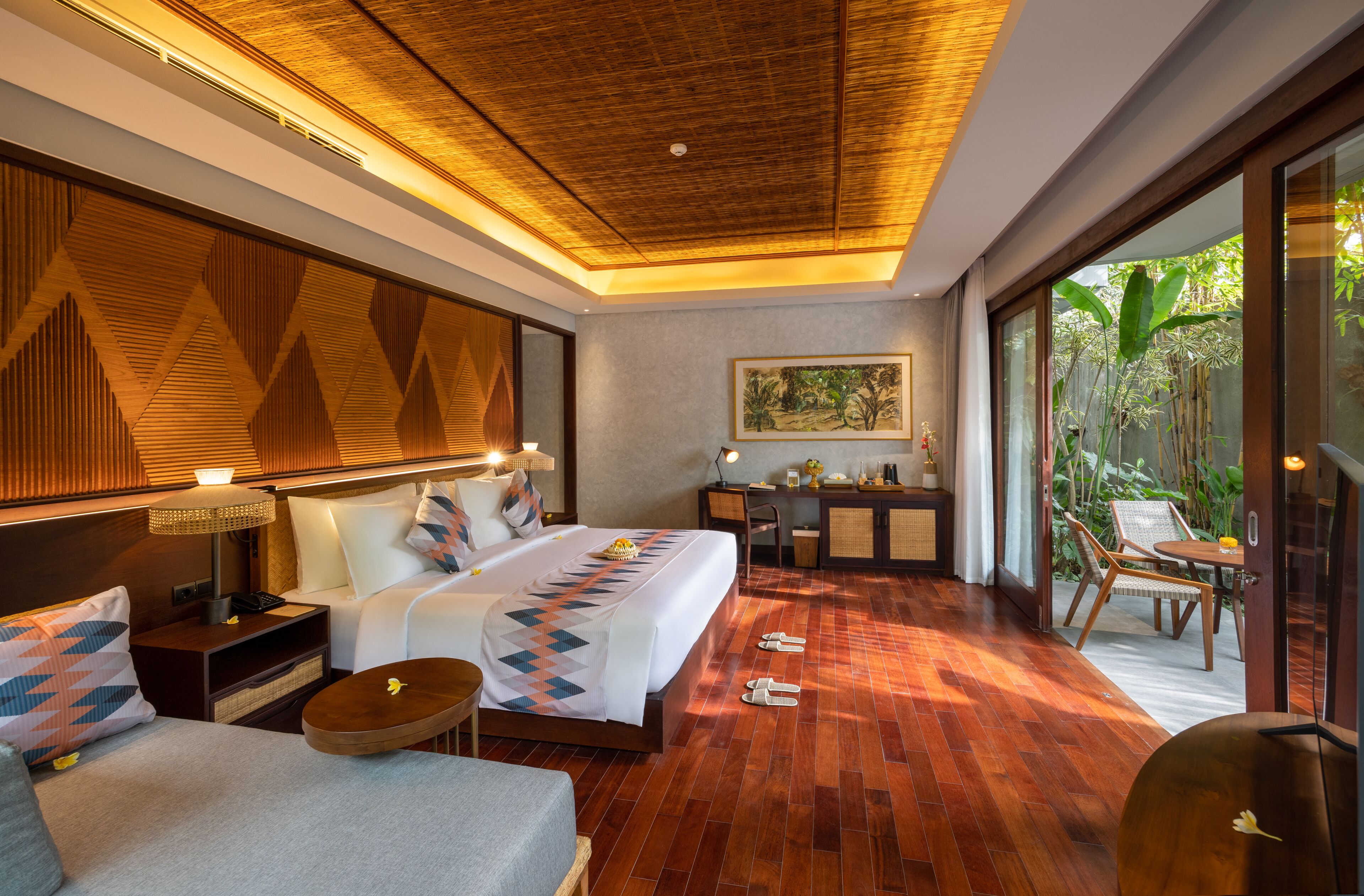 A hotel room with a bed, bedside tables, a desk, and a view of the outdoors.