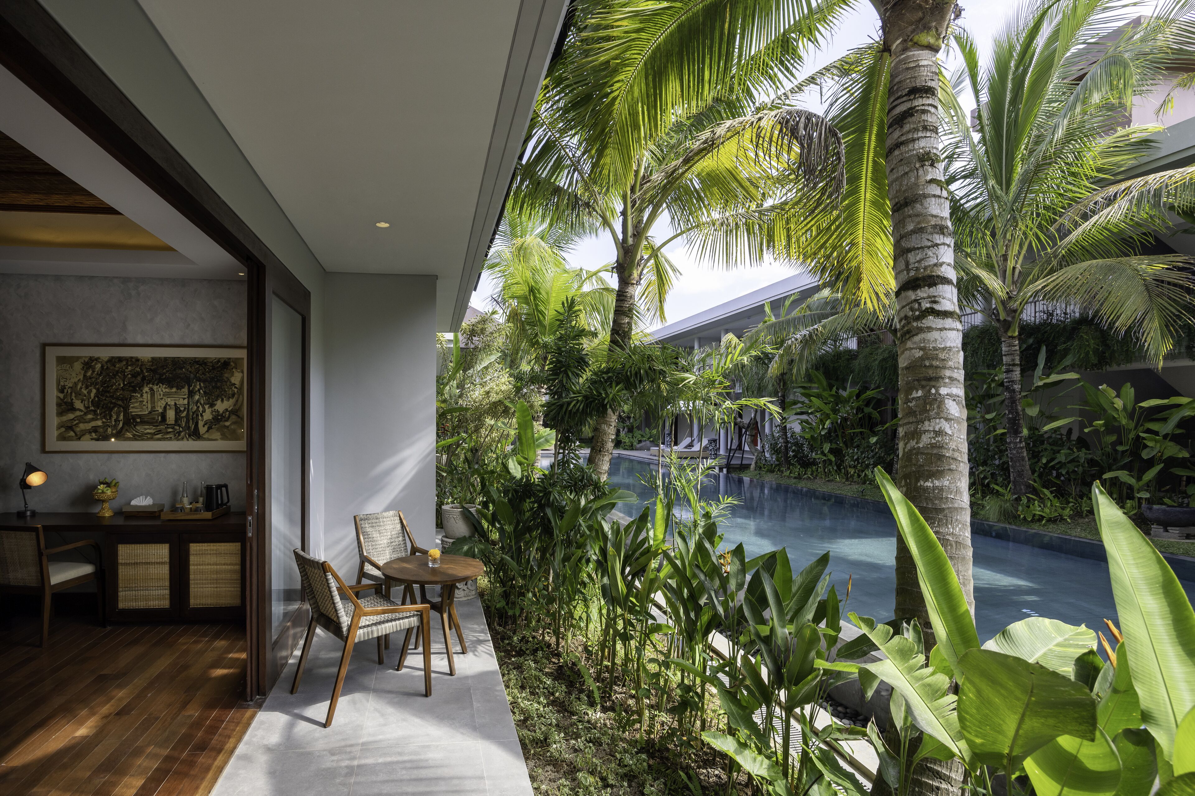 A modern interior with a dining area, a pool, and lush greenery.