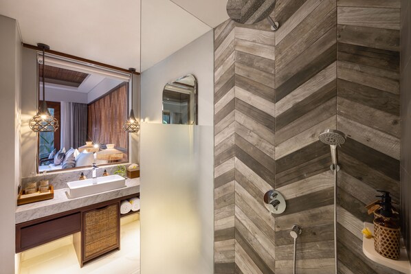 A modern bathroom with a large mirror, wooden herringbone wall, and a shower with a handheld showerhead. - The Hava Ubud A Pramana Experience (Ubud)