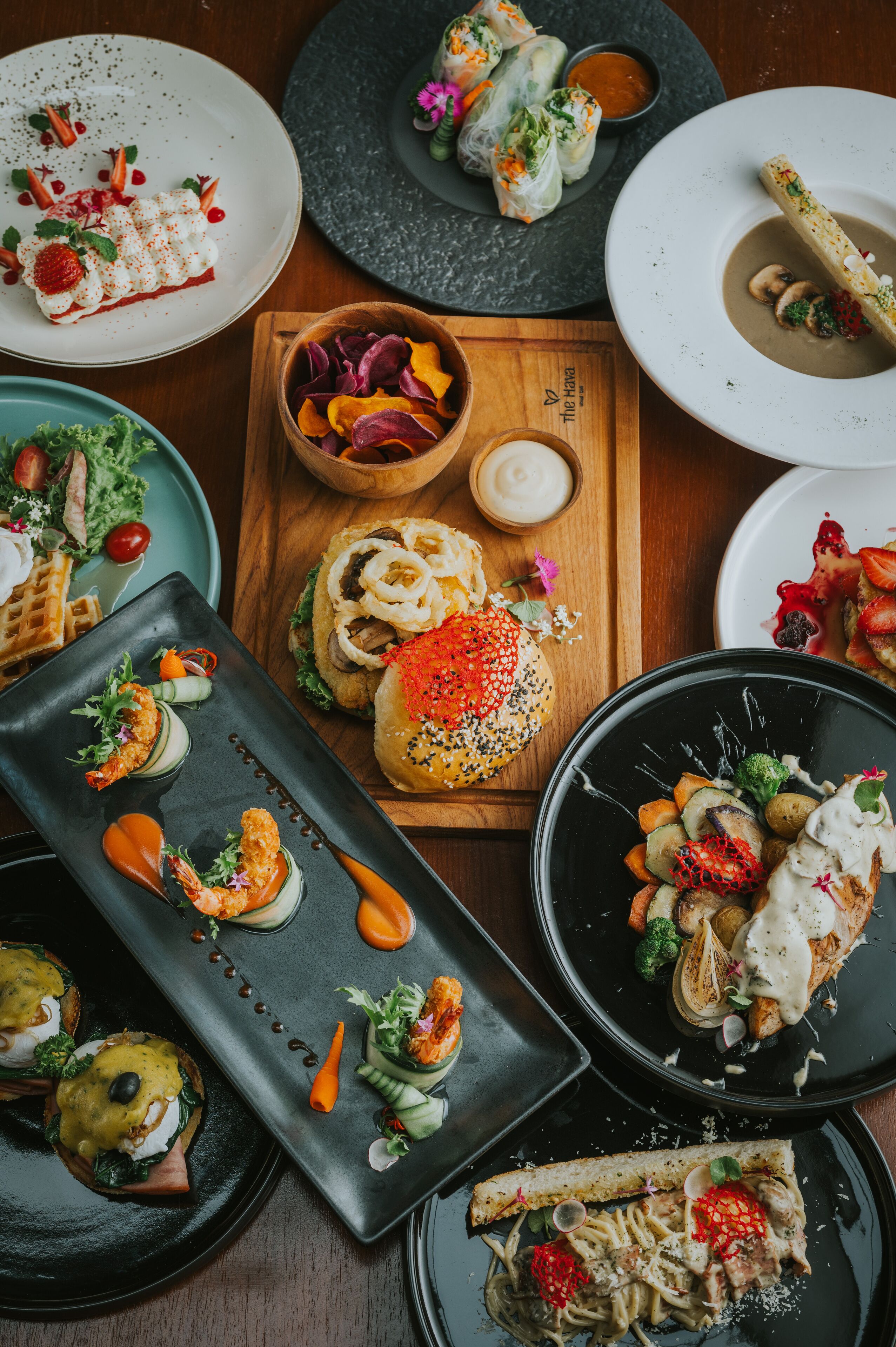 A variety of dishes on a wooden table, including sushi, pasta, and a dessert.