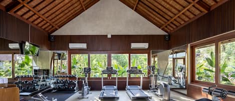Un gimnasio con cintas de correr, máquinas de pesas y equipo de ejercicio.