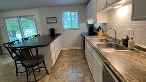 A kitchen with a dining area, featuring a kitchen island, a sink, and a dishwasher.