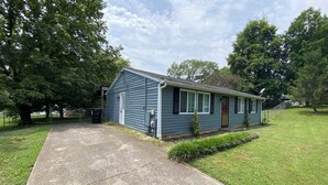 A single-story house with a front porch, a small front yard, and a driveway leading to the garage.