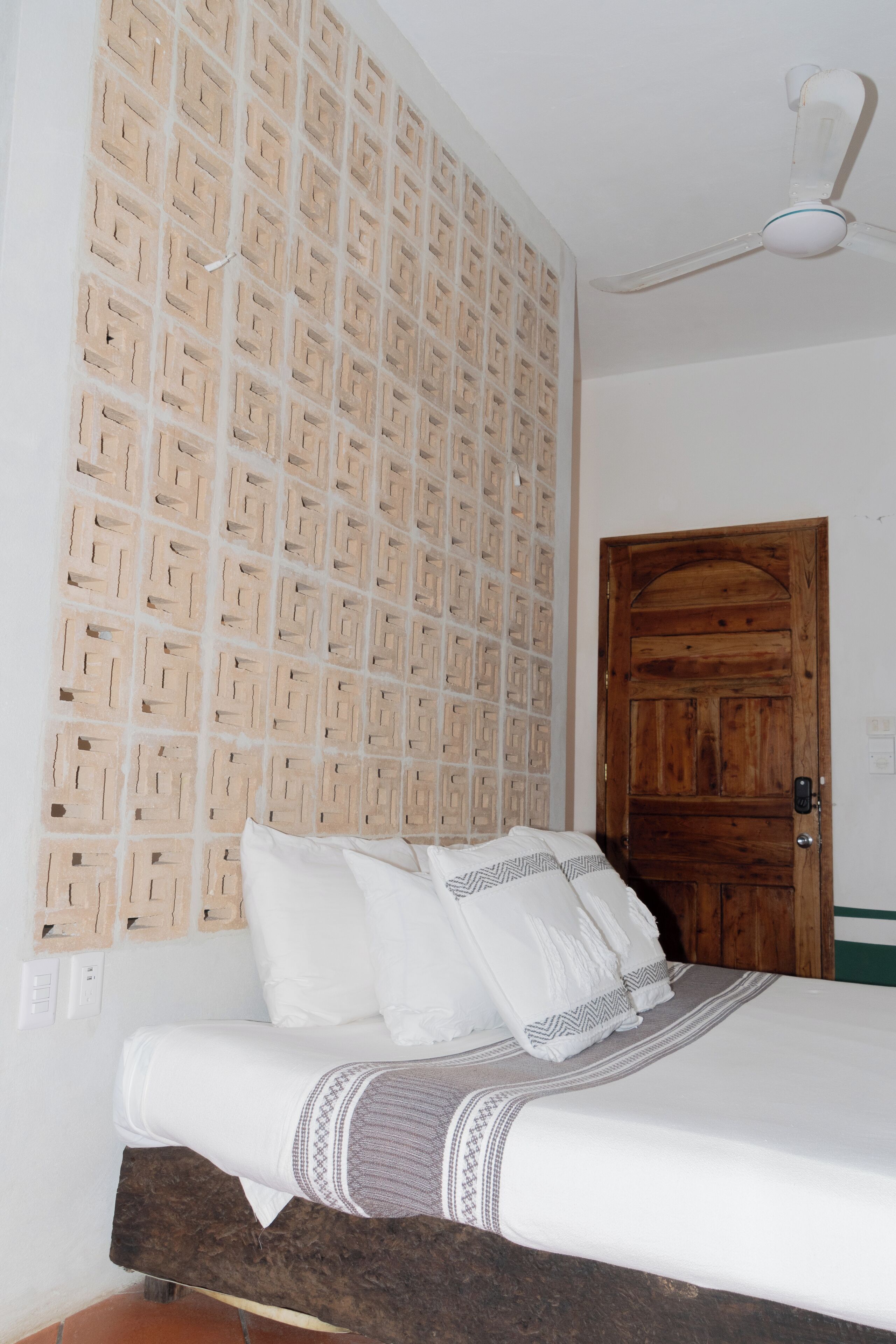 A bedroom with a bed, a wooden door, and a ceiling fan.