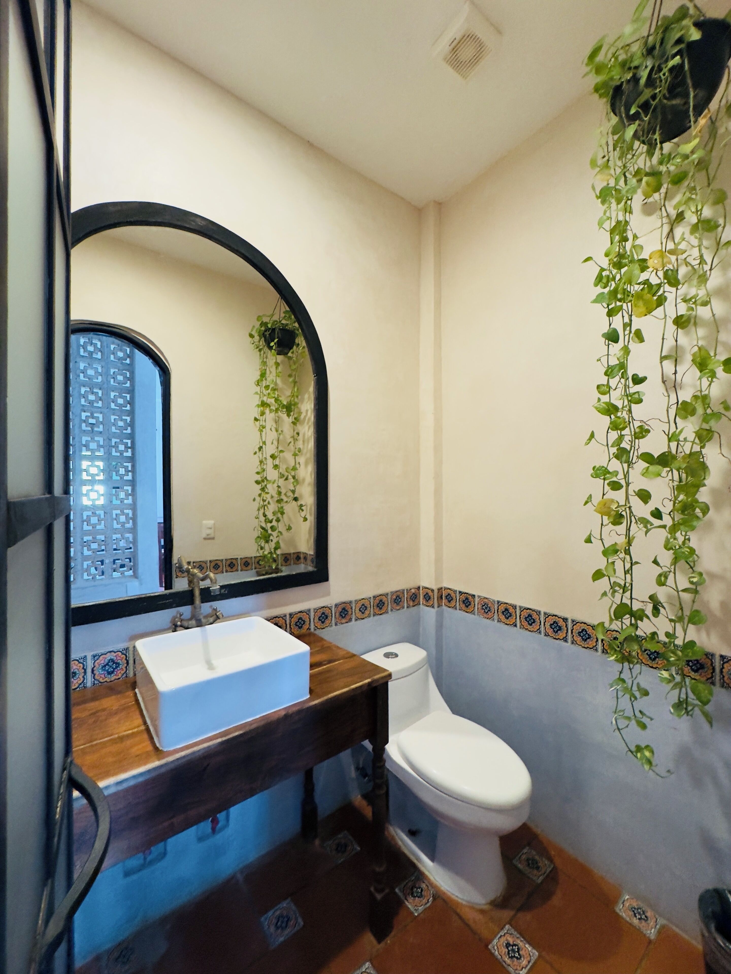 Un baño con un lavabo blanco, un inodoro y un espejo con marco negro.