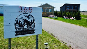 A sign with the number 365 and a logo depicting a cabin, trees, and a campfire. - Niseko Riverside by Zen Life : Greenie Cottage (New Glasgow)