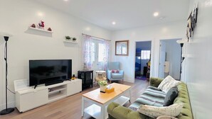 A modern living room with a flat-screen TV, a sofa, a coffee table, and a fireplace. - Niseko Riverside by Zen Life : Greenie Cottage (New Glasgow)
