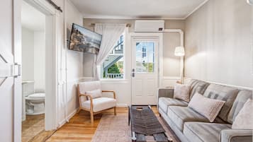 Un salon moderne avec un canapé, un fauteuil, une table basse et un téléviseur fixé au mur.