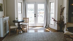 A room with a dining area, a large window with curtains, a radiator, and a potted plant. - Admirals Quarters Inn (Boothbay Harbor)