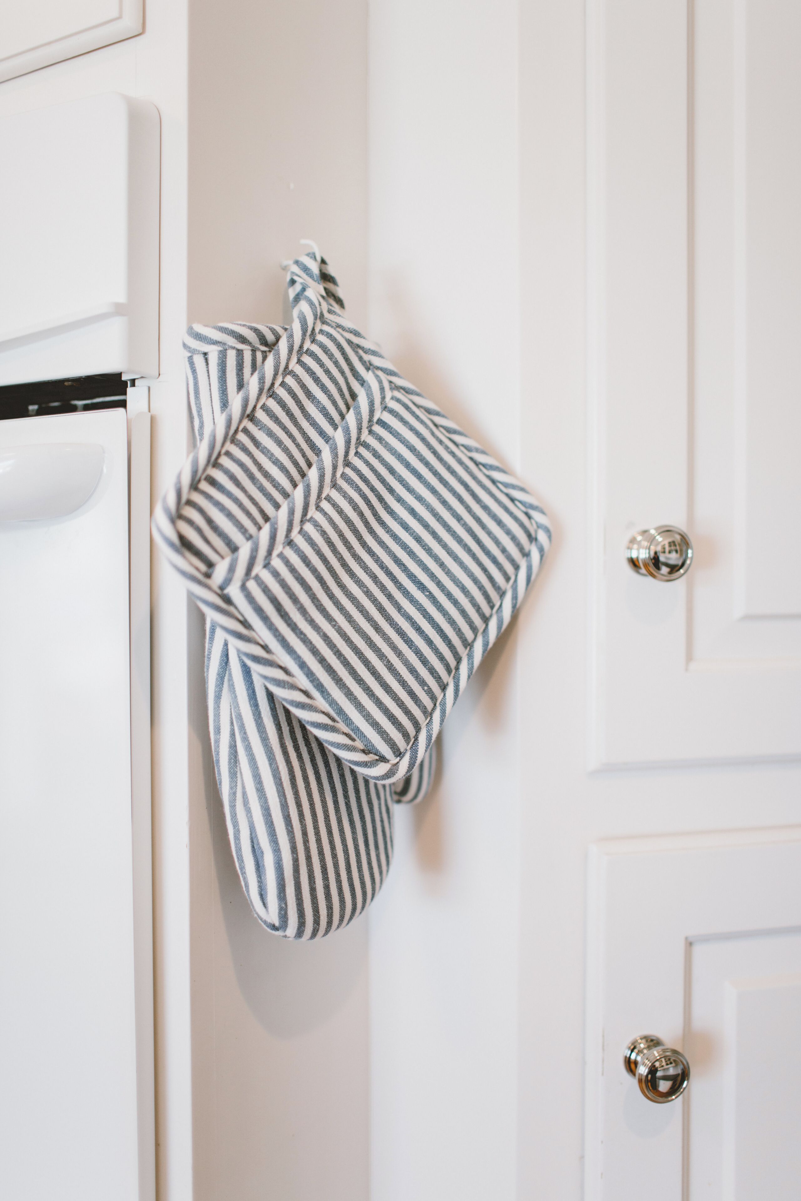 A kitchen with white cabinets and a striped towel hanging on the door handle.