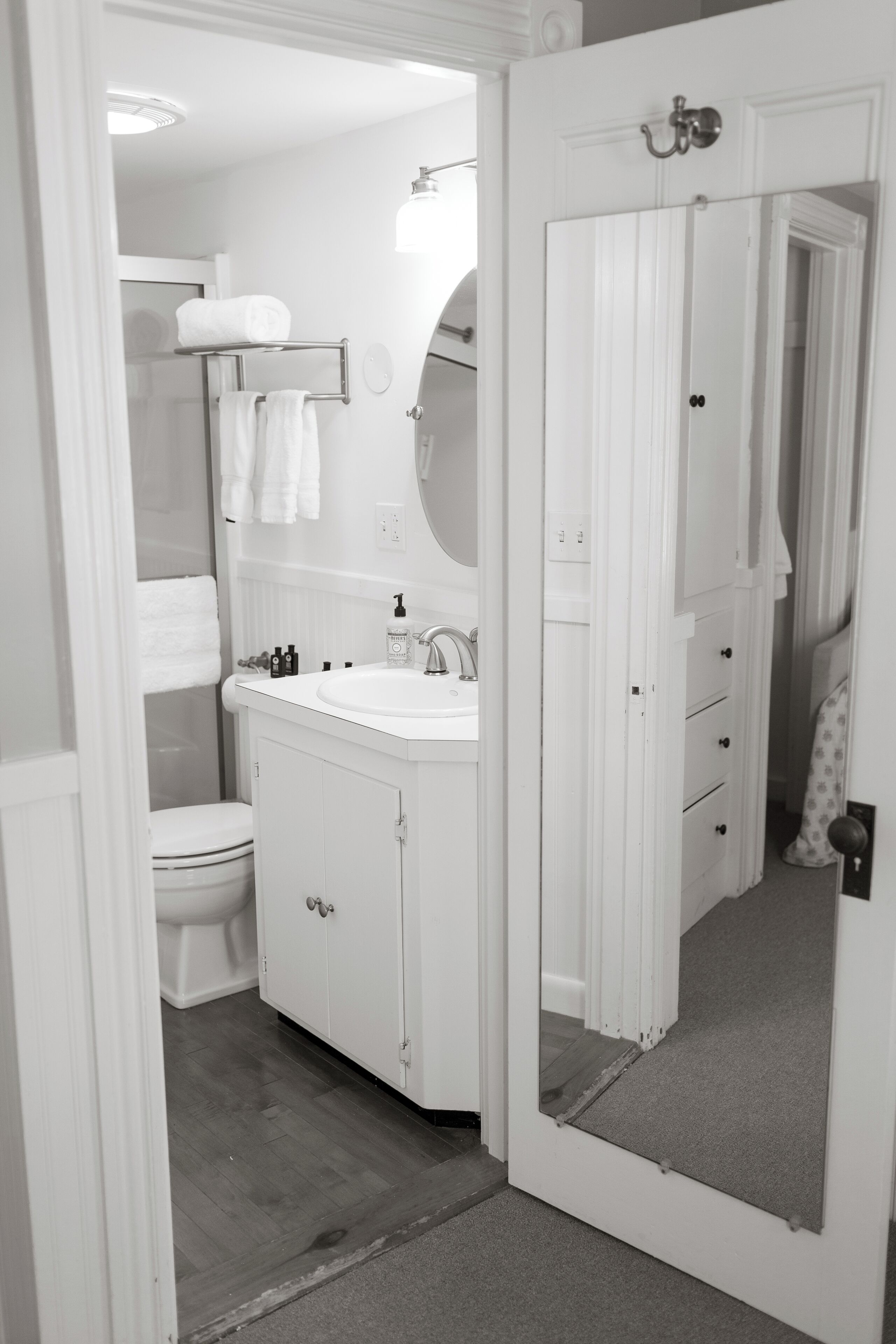 A bathroom with a white sink, mirror, and toilet. There are towels on a rack and a shower curtain.