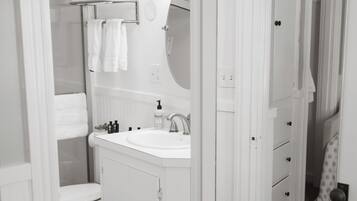 A bathroom with a white sink, mirror, and toilet. There are towels on a rack and a shower curtain.