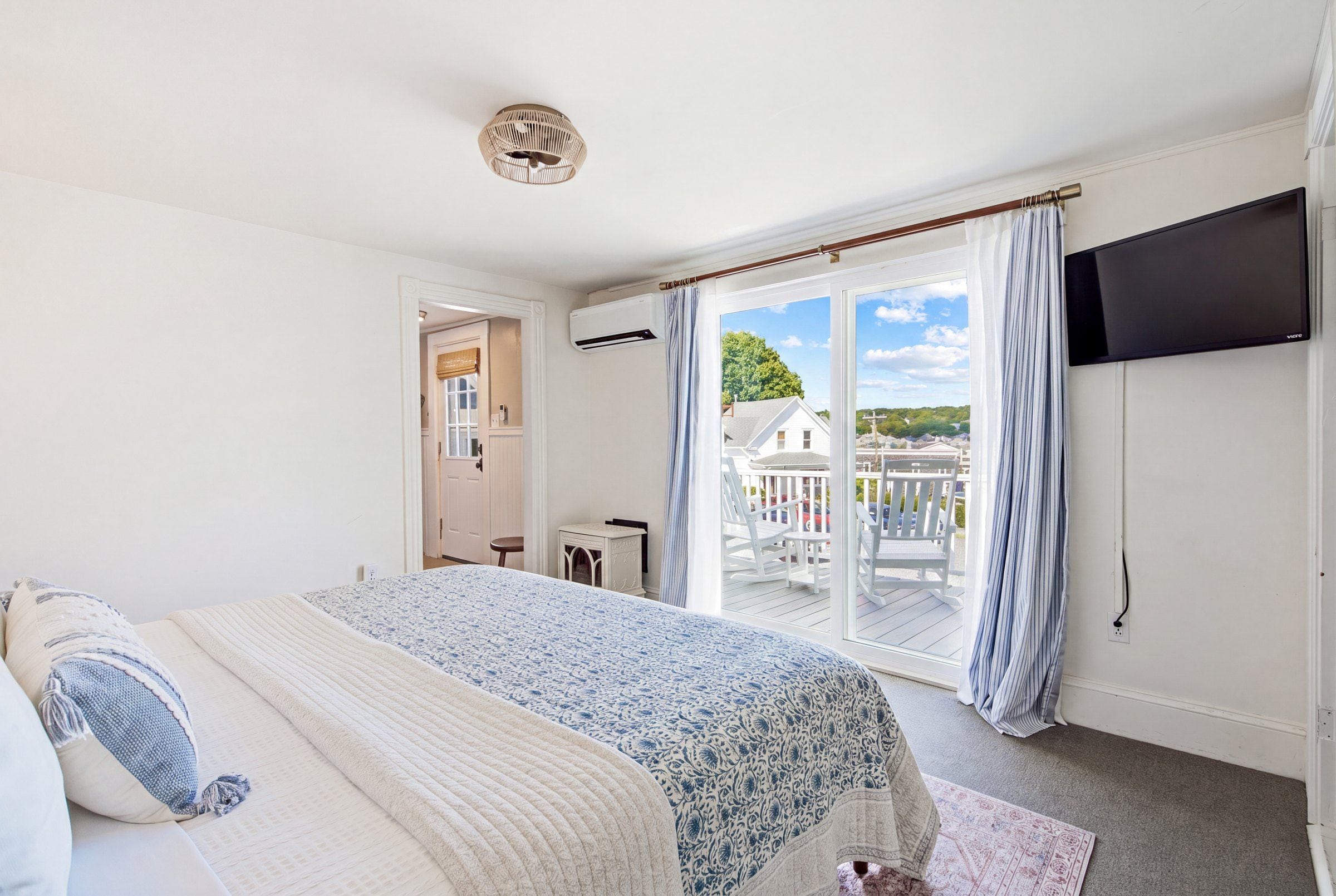 A bedroom with a bed, a TV, and a view of the outside.