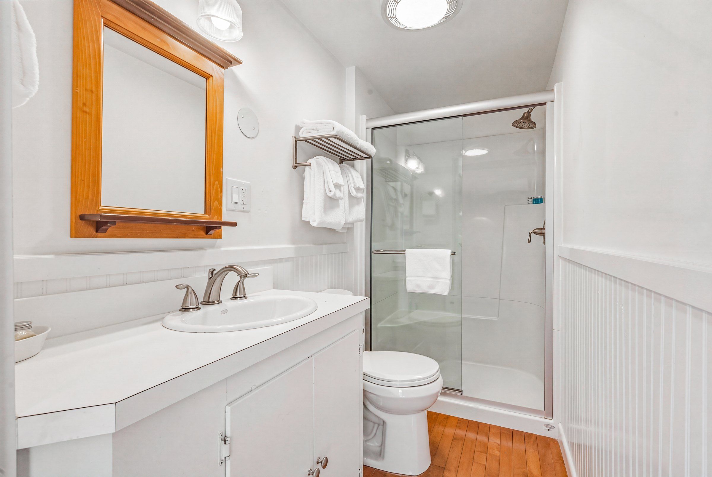 Une salle de bain avec deux éviers, des toilettes et une douche à parois de verre.