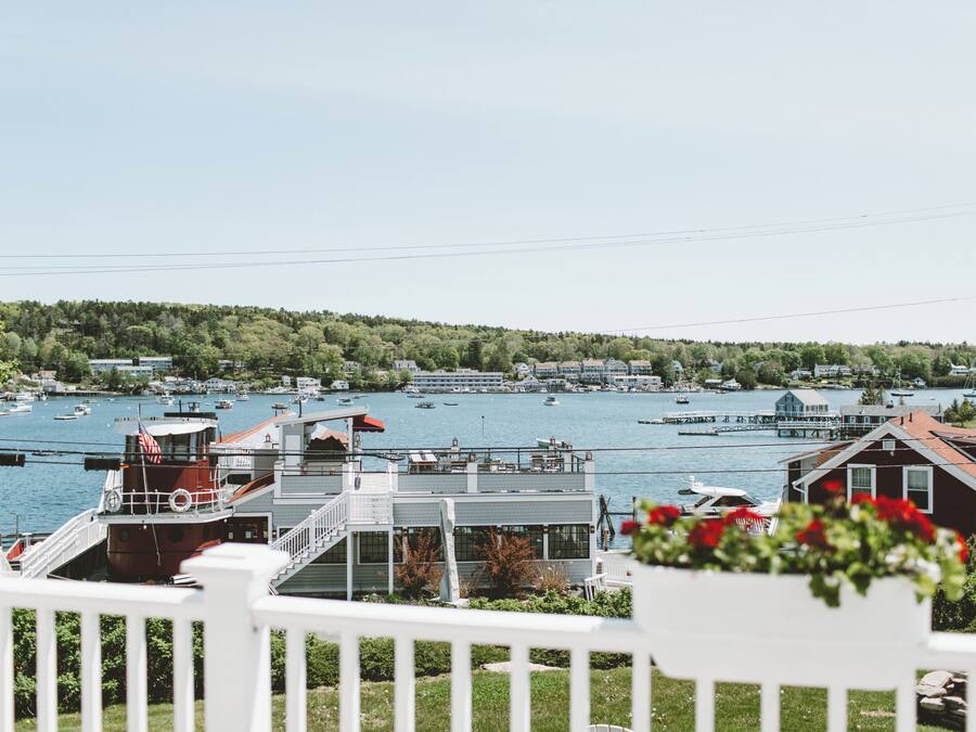 A waterfront view with boats, a dock, and a building with a red roof.