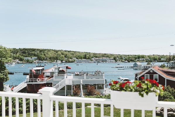 A waterfront view with boats, a dock, and a building with a red roof.