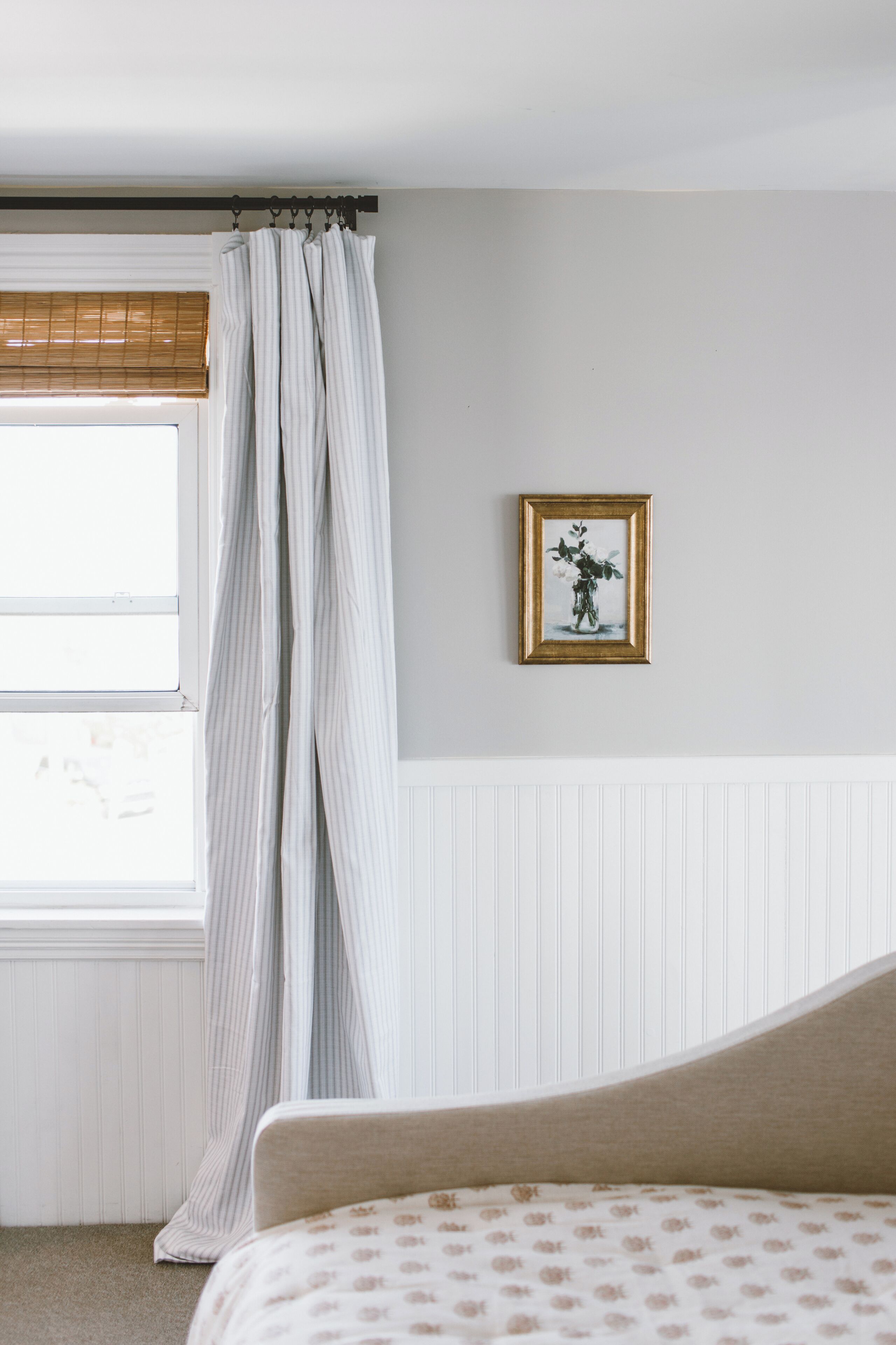 A bedroom with a bed, a window with curtains, a wall-mounted picture, and a radiator.
