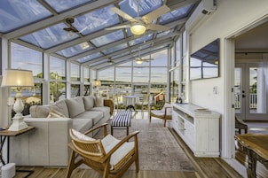 A conservatory with a sofa, chairs, a table, and a view of the city.