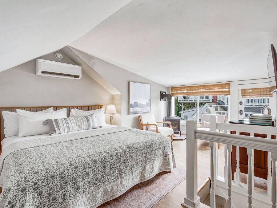 Un dormitorio con una cama, una mesita de noche, una lámpara y vistas al exterior.