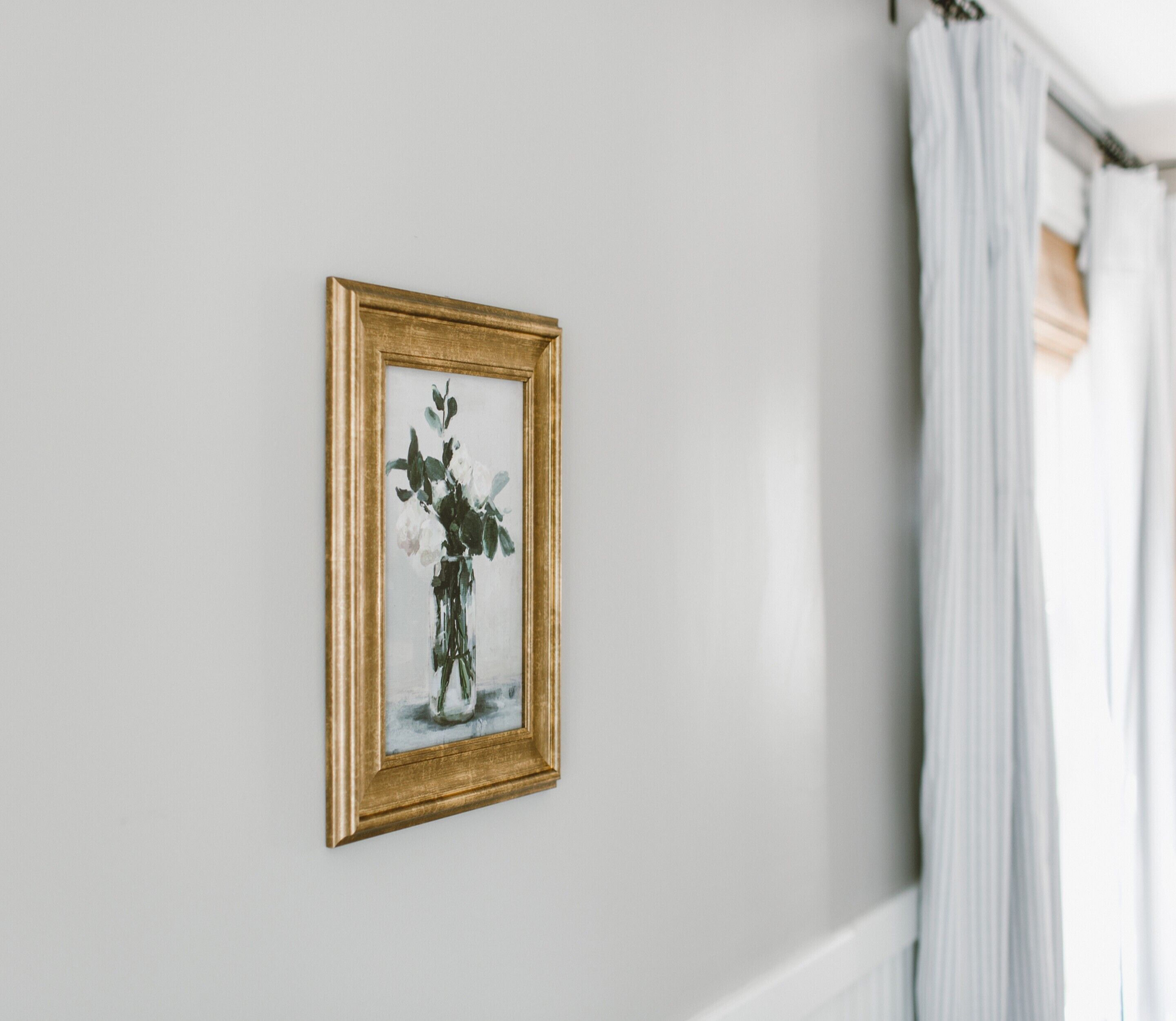 A framed artwork of a vase with flowers on a white wall.