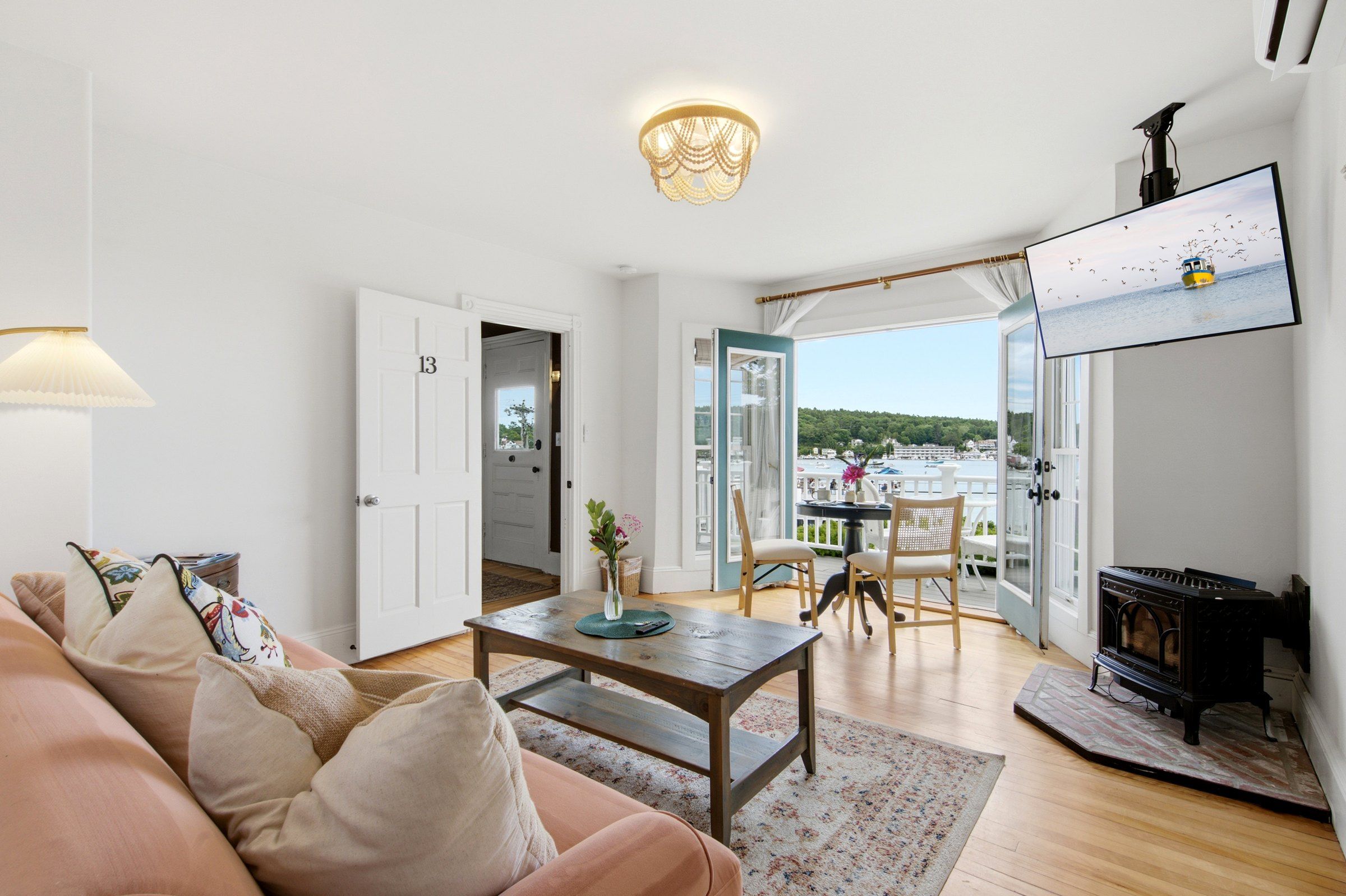 A living room with a sofa, a coffee table, a fireplace, and a view of the sea.