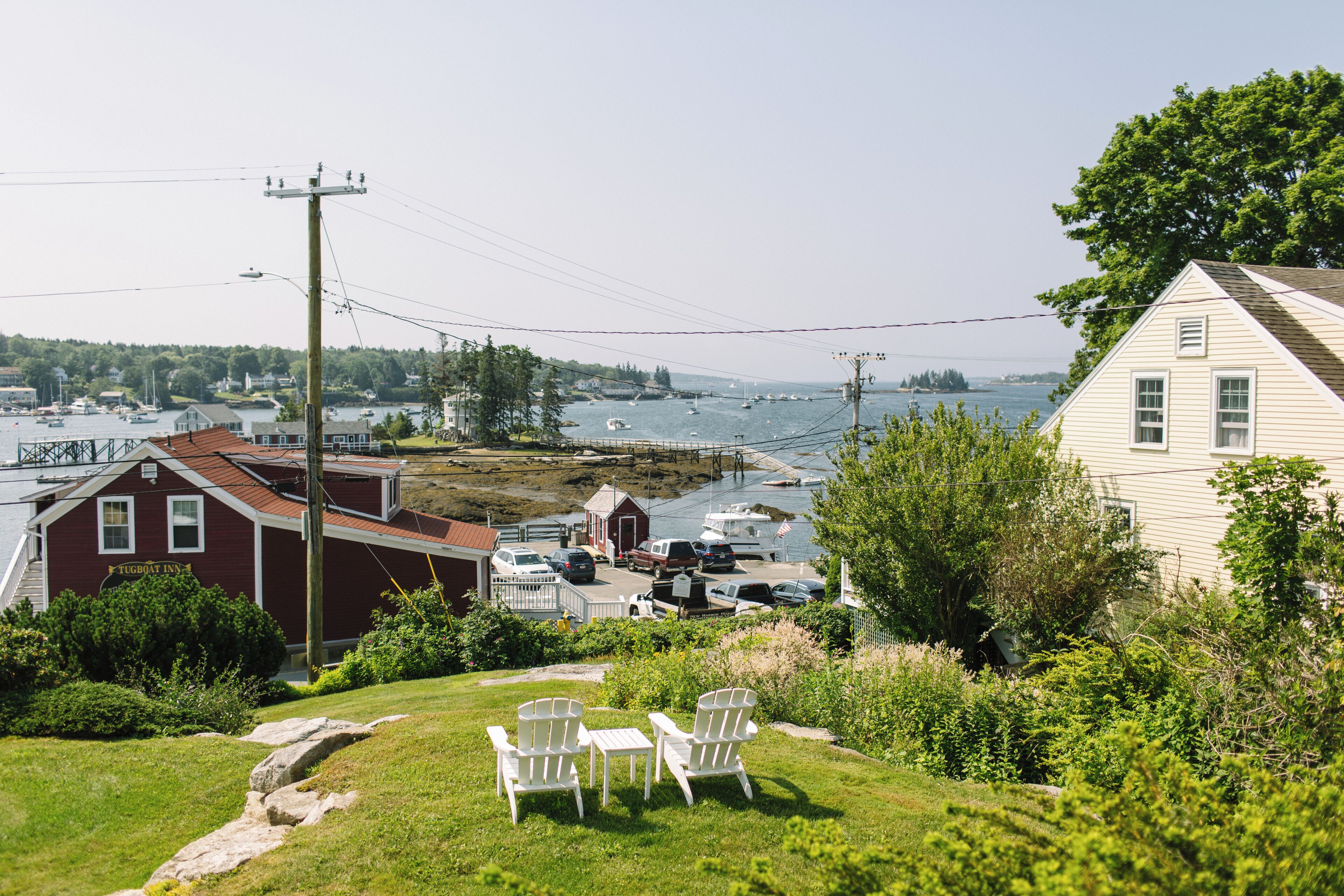 A waterfront property with a dock, a small building labeled 'Tugboat Inn', and a grassy area with outdoor seating.