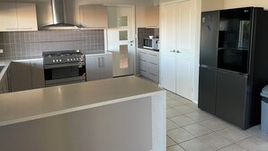A modern kitchen with stainless steel appliances, a microwave, and a refrigerator. - Gecko - On the Marina With Pool & Private Jetty, 4 Kestrel Place, Exmouth (Exmouth)