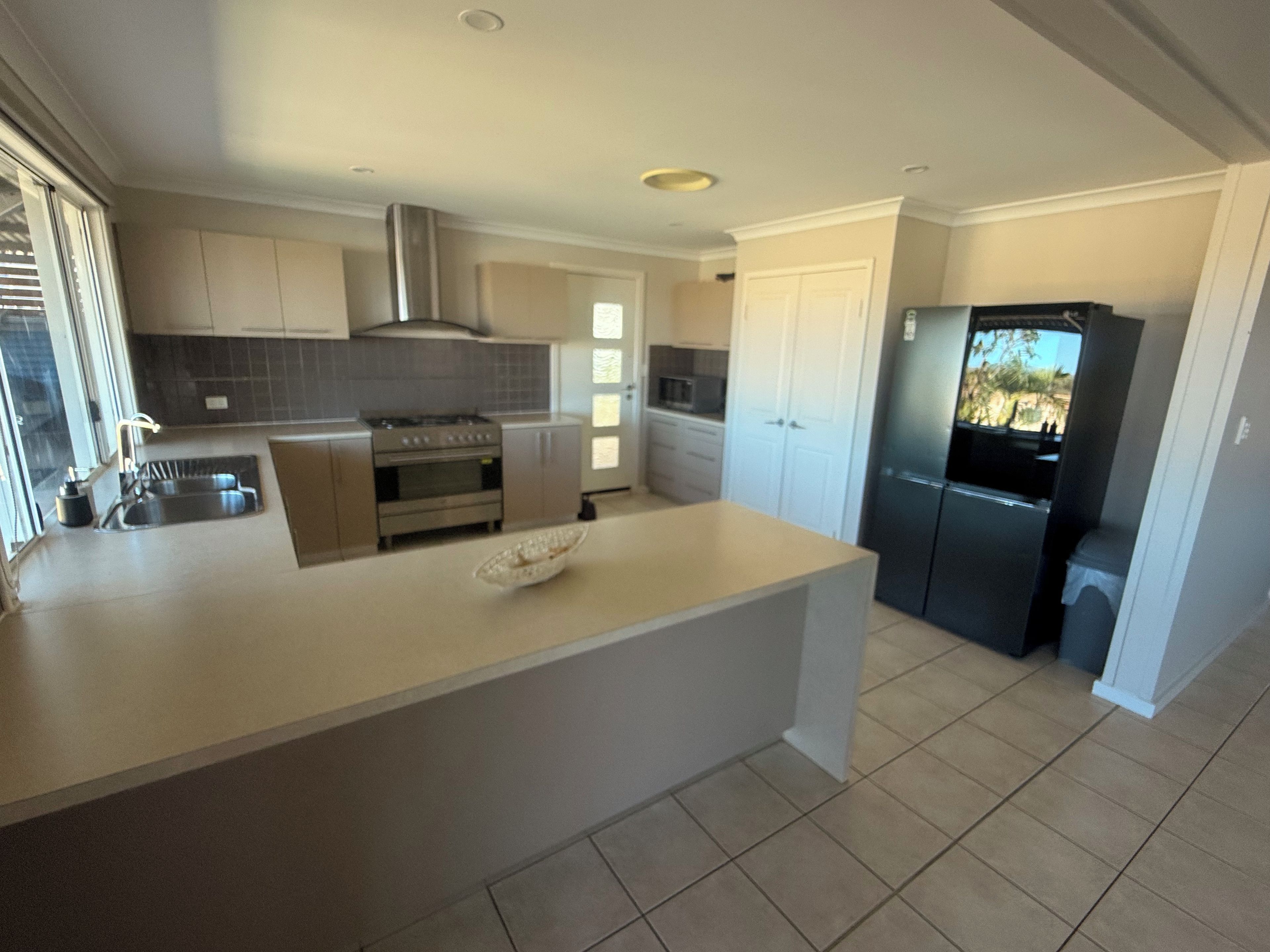 A modern kitchen with a central island, stainless steel appliances, and a view to the outdoors.