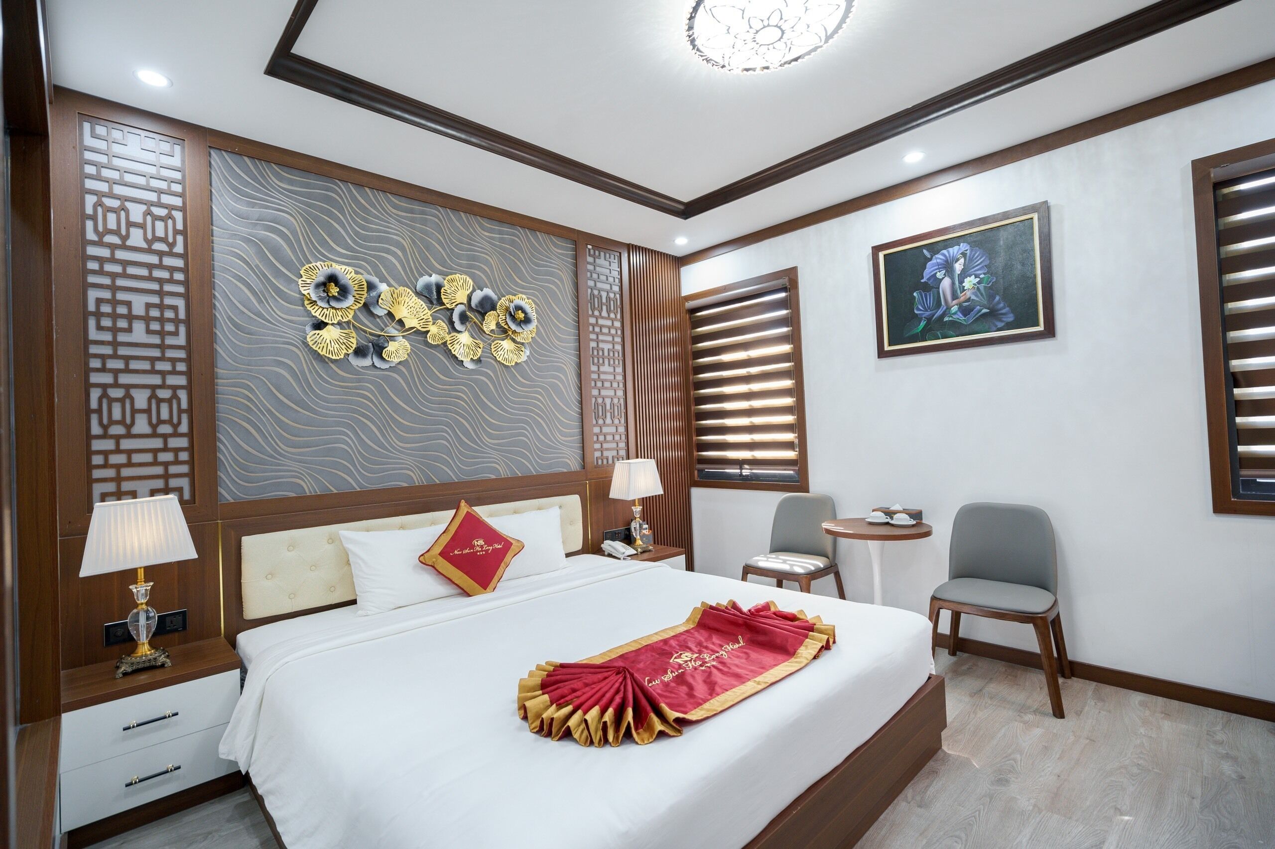 A hotel room with a neatly made bed, a bedside table with a lamp, a small round table, and a chair.