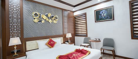 A hotel room with a neatly made bed, a bedside table with a lamp, a small round table, and a chair.