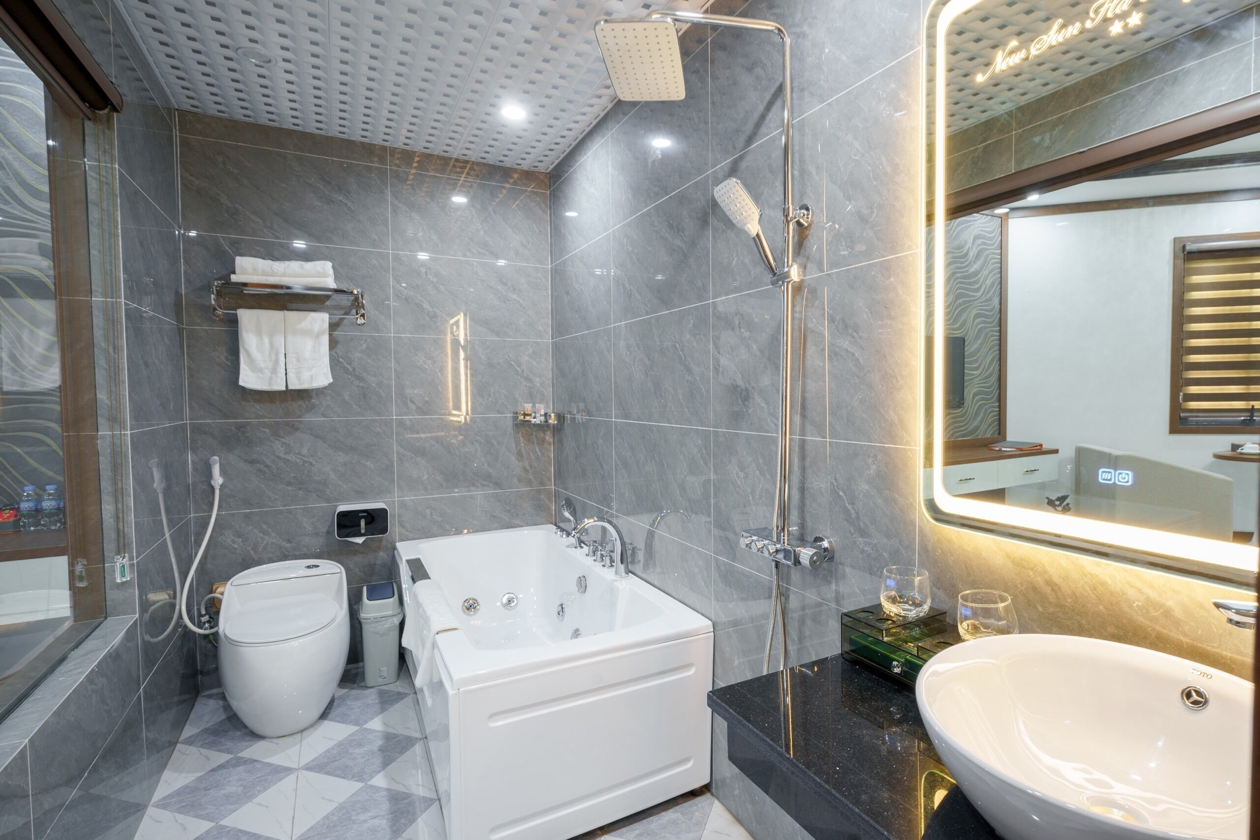 A modern bathroom with a large bathtub, a separate toilet, a shower area, and a vanity with a sink and mirror.