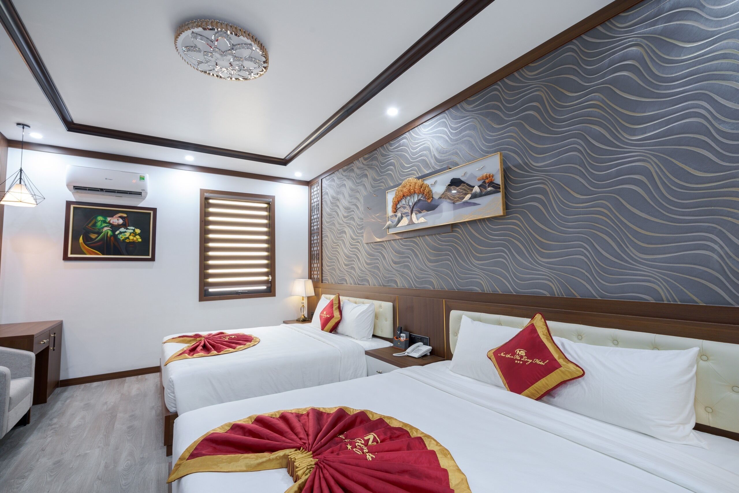 Een hotelkamer met twee bedden, een bureau, een stoel, een schilderij en een behang met patroon.