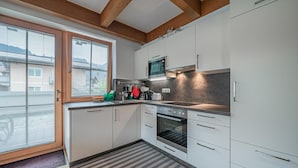 A modern kitchen with white cabinets, a built-in microwave, and a stainless steel oven.