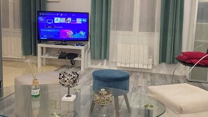 Un soggiorno con un tavolino in vetro, una TV su un mobile, un divano e una poltrona rossa.