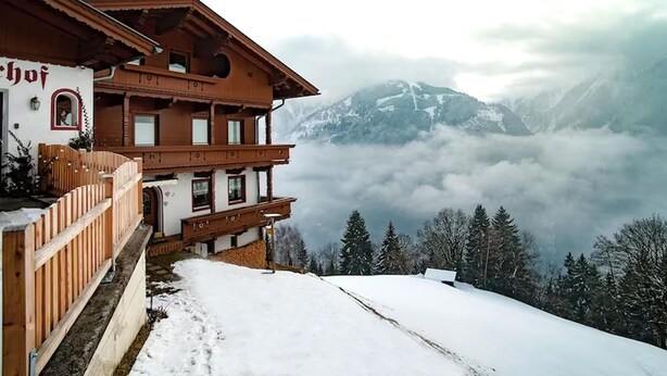 A chalet-style building with a wooden facade and a balcony, overlooking a snowy mountain landscape and forested area. - Beautiful apartment in a dream location in Finkenberg (Finkenberg)