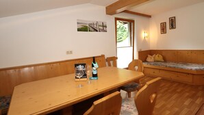 A dining area with a wooden table, chairs, and a bench. There is a window with a view of greenery outside. - Beautiful apartment in a dream location in Finkenberg (Finkenberg)