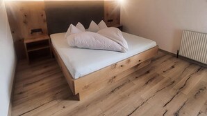 A small, modern bedroom with a wooden bed, a nightstand, and a radiator. - Beautiful apartment in a dream location in Finkenberg (Finkenberg)