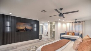 A modern bedroom with a bed, a ceiling fan, a wardrobe, and a painting on the wall.