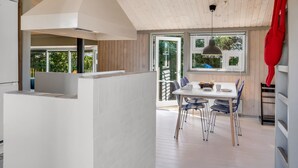 A modern kitchen with a central island, a dining area with a table and chairs, and a large window providing natural light. - "Lazorka" - 450m from the sea by Interhome (Løkken)
