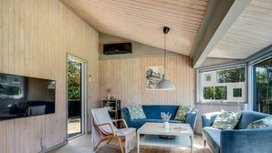 A modern living room with wooden walls, a blue sofa set, a coffee table, and a TV mounted on the wall. - "Lazorka" - 450m from the sea by Interhome (Løkken)