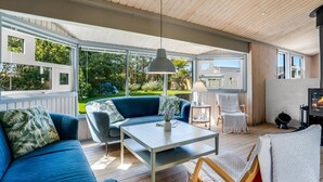 A sunlit room with a blue sofa, a table, and a chair. - "Lazorka" - 450m from the sea by Interhome (Løkken)