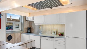 A modern kitchen with white cabinets, a built-in microwave, a coffee maker, and a sink. - "Lazorka" - 450m from the sea by Interhome (Løkken)