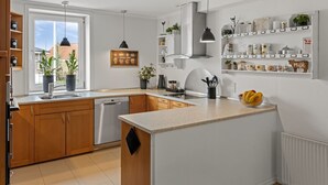 Eine moderne Küche mit einer zentralen Kochinsel, eingebauten Regalen und Blick durch ein großes Fenster.