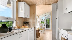 Een moderne keuken met witte kasten, een koffieapparaat en een eethoek met een tafel en stoelen.