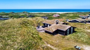A coastal village with traditional houses, a sandy beach, and the ocean in the background.