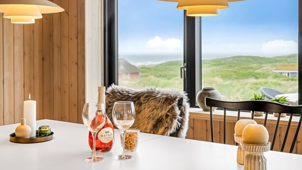 A dining table with a bottle of Mateus wine, two glasses, a candle, and a fur throw.