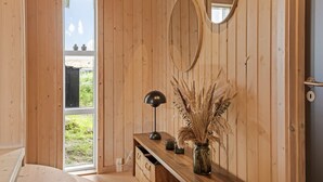 A wooden room with a desk, a lamp, and a vase with dried plants.