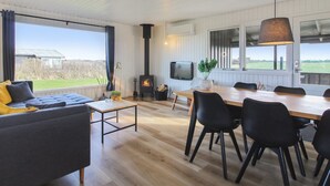 A spacious living area with a large window, a fireplace, and a dining table with chairs. - "Lok" - 450m from the sea by Interhome (Løkken)
