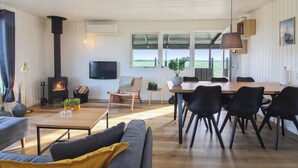 A spacious living area with a fireplace, a TV mounted on the wall, a dining table with chairs, and a sofa with cushions. - "Lok" - 450m from the sea by Interhome (Løkken)